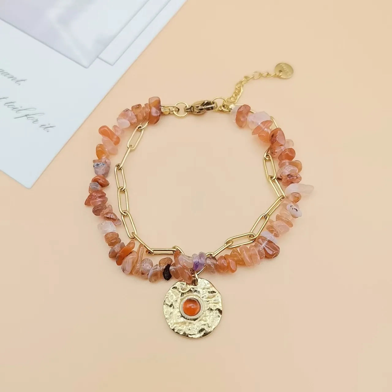 Bracelet with multicolored beads and a gold charm on a beige background