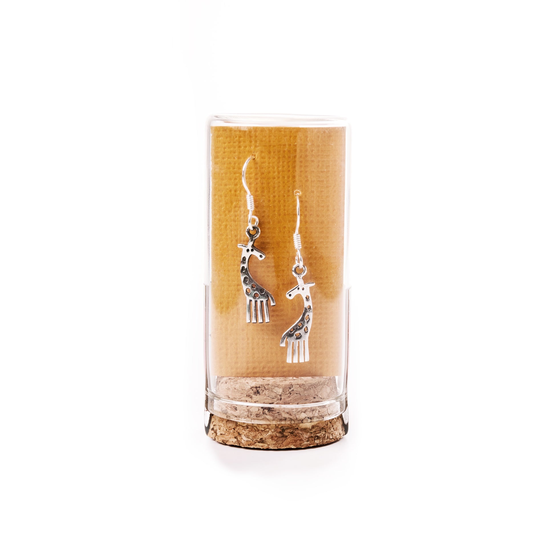 Silver giraffe-shaped earrings in a clear cylindrical container with cork base on a white background